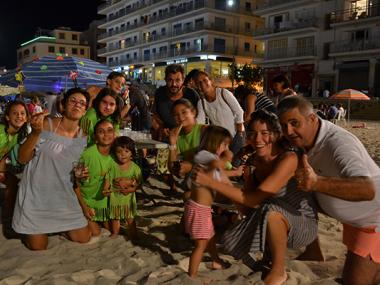 La sombrillada nocturna de les festes de s’Illot uneix generacions de silloters i silloteres en el sopar a la platja