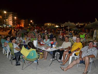 La sombrillada nocturna de les festes de s’Illot uneix generacions de silloters i silloteres en el sopar a la platja